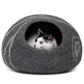 a cat sits inside a dark grey cat cave
