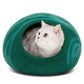a cat sits inside a green cat cave